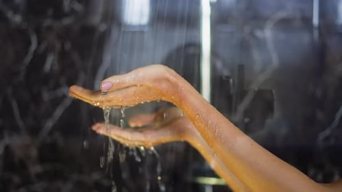 Water Flowing Over Woman's Hands in Shower