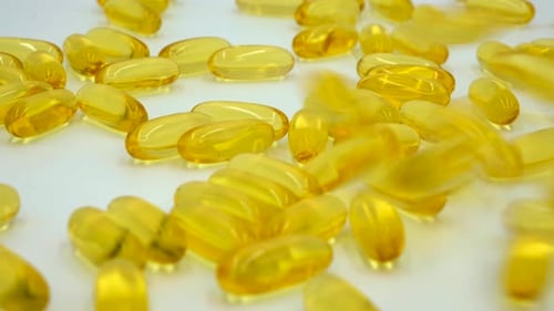 Yellow Gel Capsules Scattered on White Surface