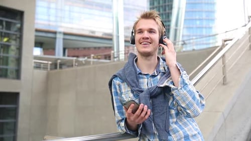 Man Enjoys Music with Headphones in City