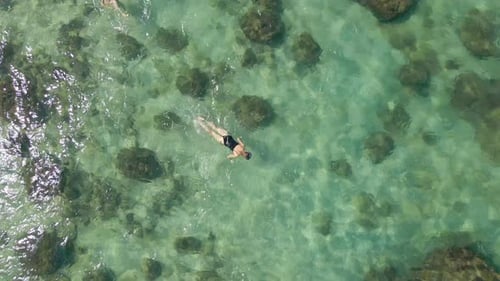 Aerial Slowmotion Shot of a Young Woman Snorkeling in a Clear Blue Sea Water