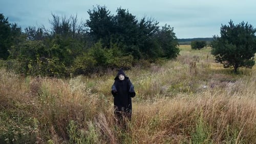 Scary death in black. Spooky figure in black mantle standing alone on the field