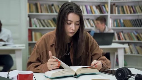 Modern Young Woman with Long Hair Reading Book in the University Library and then Looking Aside