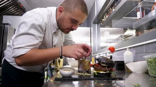 Cook in Restaurant Kitchen Placing Fried Potatoes