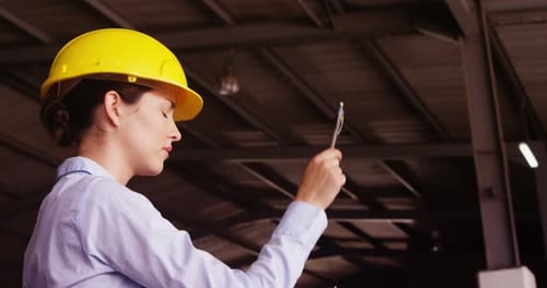 Female supervisor maintaining record on clipboard
