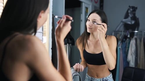 Reflection of Young Beautiful Woman Applying Her Make-up