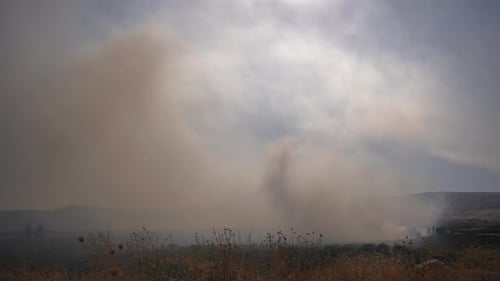 Smoke rises above the field on fire