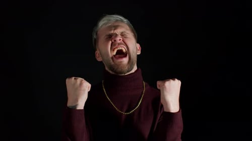 Man Celebrates Success Clenching Fists Against Black Background