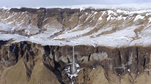 Kleiner und schöner Wasserfall auf einem schneebedeckten Felsvorsprung im Winter