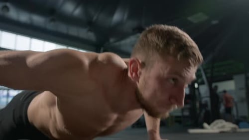 Young male athlete trains in the gym, push-ups from the floor, crossfit, endurance training