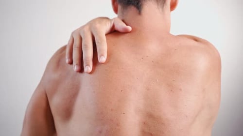 Man Rubs Sore Shoulder and Back Muscles
