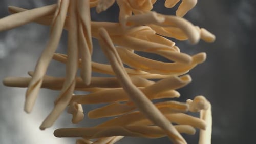 Camera follows throwing riccioli pasta into water. Slow Motion.
