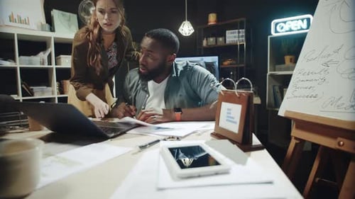 Female Professional Checking Work of Afro Man Near Laptop in Dark Office.