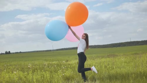 Happy Girl with Big Multicolored Balloons Posing on the Field