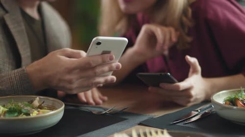 Couple Using Phones at Restaurant Table