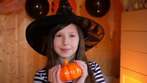 Girl in Witch Hat Holding Pumpkin Decoration