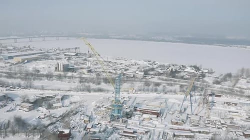 Baustelle mit Kränen und verschneiten Stadtstraßen