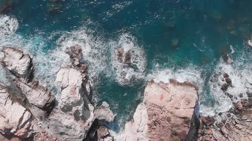 Ocean waves crashing steep coastline cliff. Rocky seashore and waves.