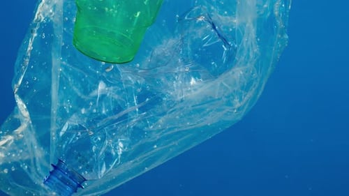 Closeup of Plastic Glasses and Bottles in Ocean Water Pollution Concept