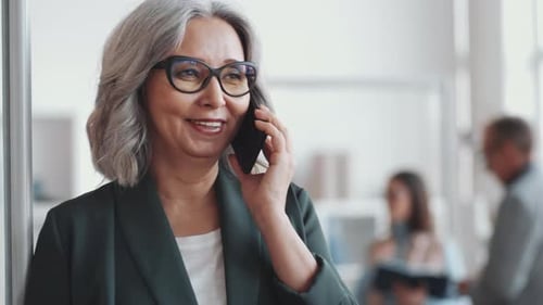 Beautiful Senior Business Lady Speaking on Mobile Phone in Office