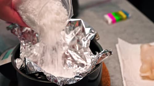 Few women occupied with hand made candles production, adding wax to a pot