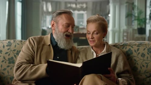 Pareja de ancianos recordando momentos felices con álbum de fotos