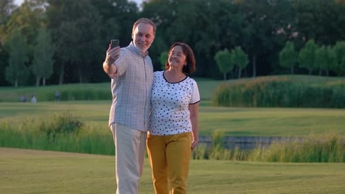 Happy Mature Couple Relaxing at Park Using Smartphone.