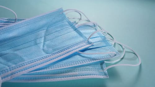 Surgical Masks Stacked on Light Blue Surface
