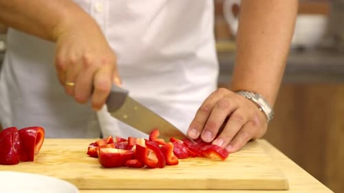 Nahaufnahme Man schneidet frischen roten Pfeffer in Scheiben und kocht vegane gesunde Beilage