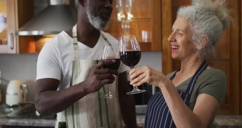 Senior Couple Toasting with Red Wine in Kitchen
