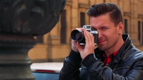 A Young Handsome Man Takes Photos of a Statue with a Camera - Closeup - a Busy Street