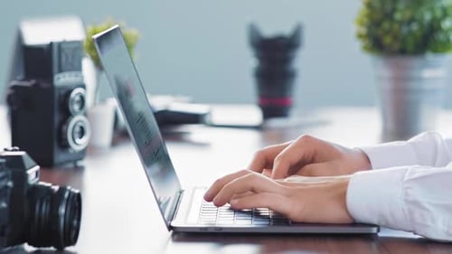 Hands Typing on Laptop in Office with Camera
