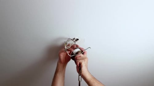 Hands Repairing Light Fixture with Electrical Wires