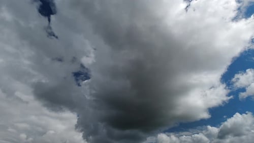 Clouds pass by blue sky as weather changes to rain cloud, time lapse