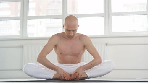 Muscular Man Stretching in Bright Room