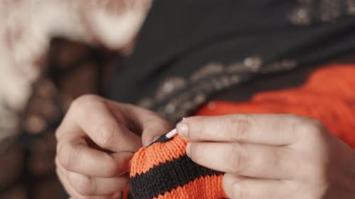 Close up of woman's hands doing the knit work tie-up hand work with black wool and two needle crafts