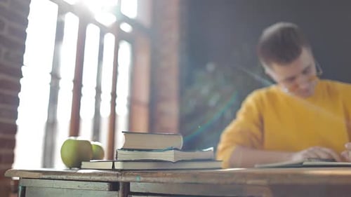 Man Writing in Notebook at Desk with Apples
