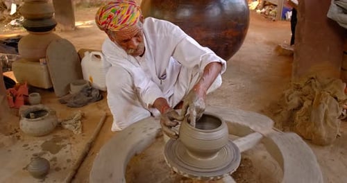 Potier professionnel qualifié lançant le tour du potier et façonnant un récipient en céramique traditionnel