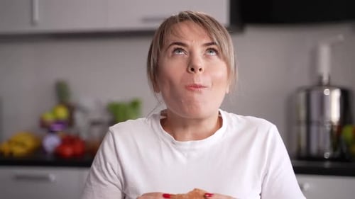 Woman Enjoying Burger in Home Kitchen