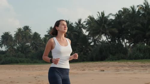 Woman Runs Along Tropical Beach at Daytime