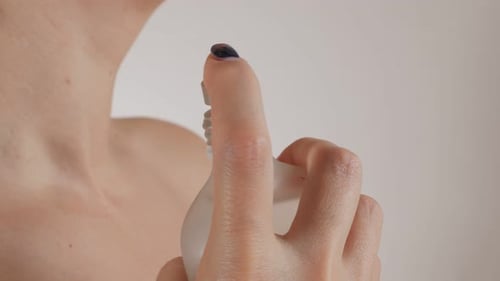 Adult Applies Perfume To Their Neck
