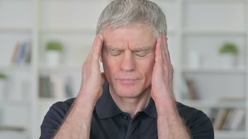 Man with Gray Hair Massaging Temples Due to Headache