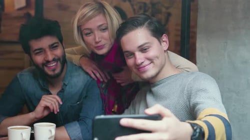 Video calling on phone. Happy friends using mobile phone in cafe