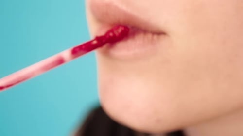 Woman Applying Red Lip Gloss Close Up