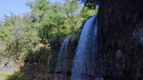 Beautiful medium shot of several waterfalls surrounded by green forest landscape in sunlight
