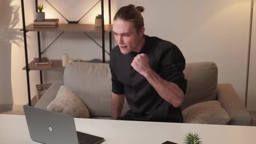 Man Celebrates Success Working On Laptop At Home