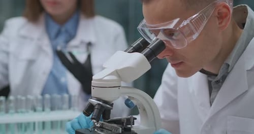 Scientist Works with Microscope in Bright Lab