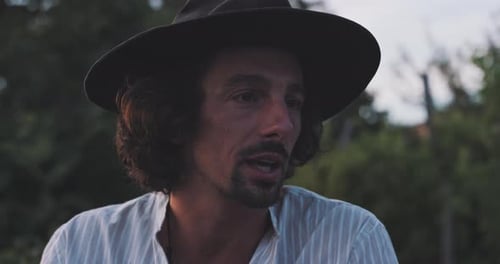 Man Speaking Outdoors Wearing Hat and Striped Shirt