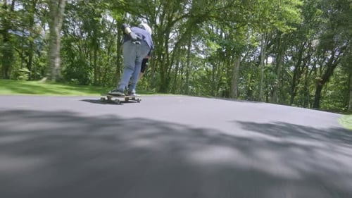 Skateboarder Rides Down Shady Park Road