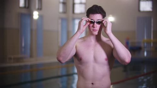 A Man Swimmer Puts on His Goggles By the Pool