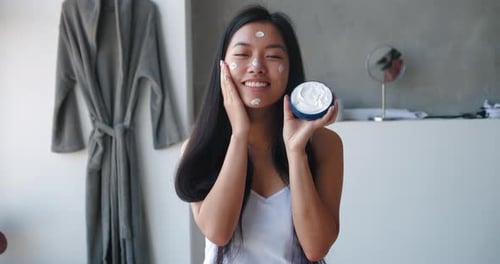 Young Woman Applies Facial Cream for Skincare